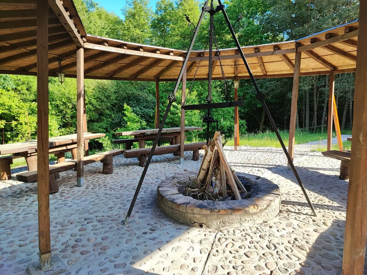 Palenisko z trójnogiem pod dużą drewnianą wiatą
